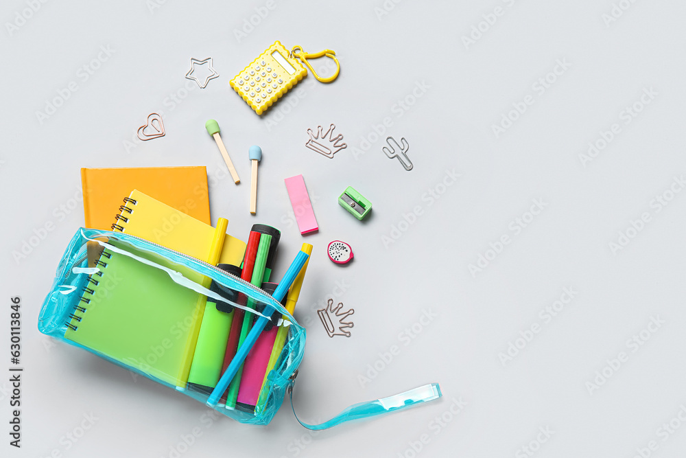 Pencil case with different school stationery on light background