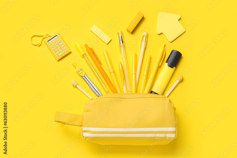 Pencil case with set of school stationery on yellow background