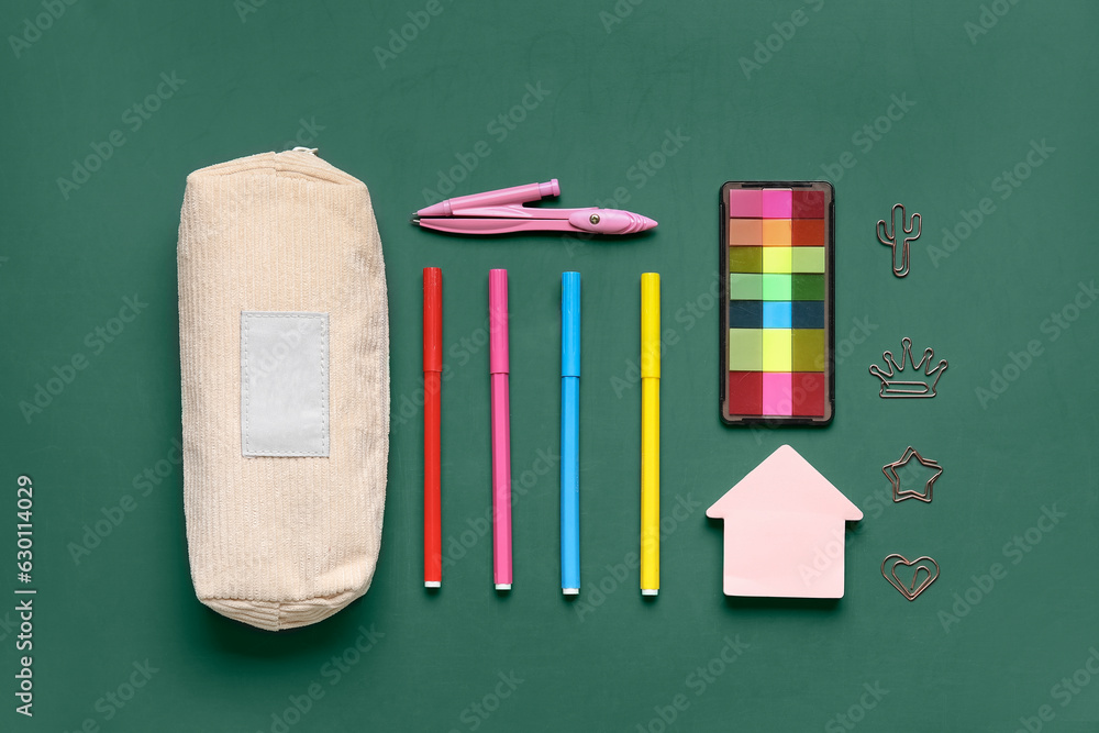 Pencil case with different school stationery on green background