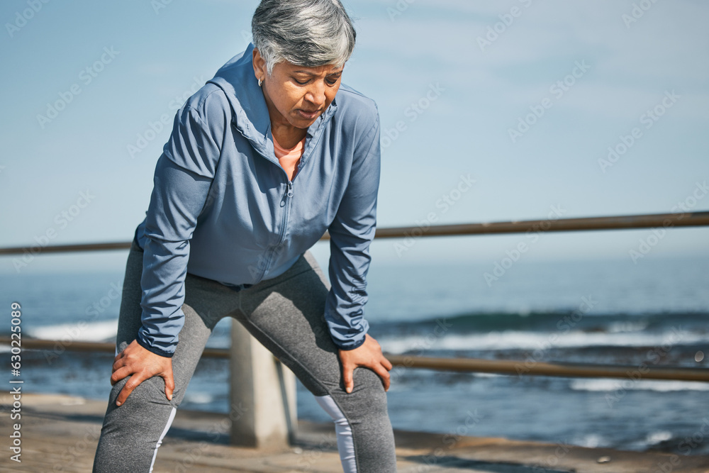 Senior, exercise and tired woman at the beach on break from training, workout or morning cardio run 