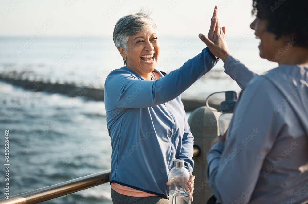 High five, fitness and senior women friends at beach with exercise, celebration and excited in natur