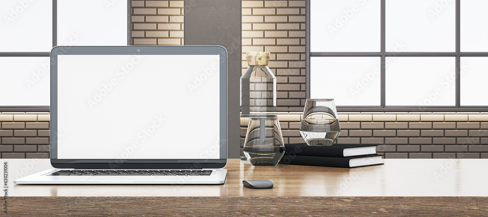 Close up of wooden office desk with empty white computer, supplies and other objects. Blurry brick w