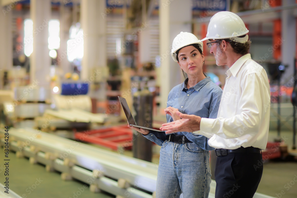 Young Beautiful engineer holding a laptop Standing and discussing with a senior male manager enginee