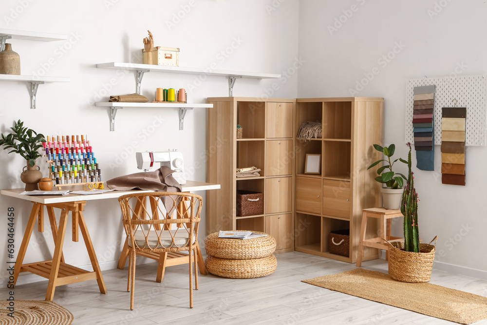 Interior of modern atelier with tailors workplace, thread spools and shelves