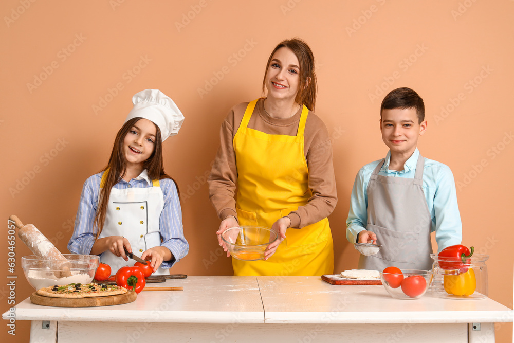 Female chef with little children during cooking class on beige background