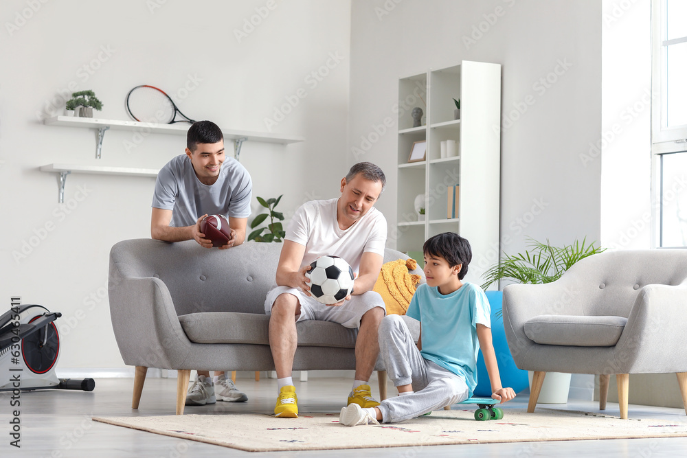 Sporty little boy with his dad and grandfather at home