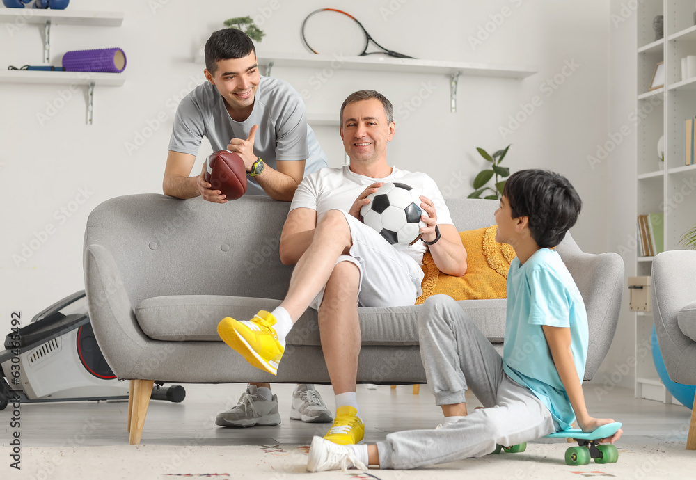 Sporty little boy with his dad and grandfather at home