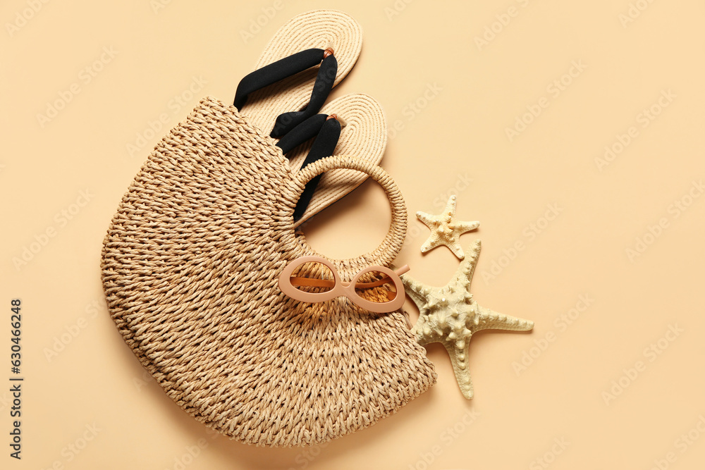 Bag with flip-flops, sunglasses and starfishes on beige background