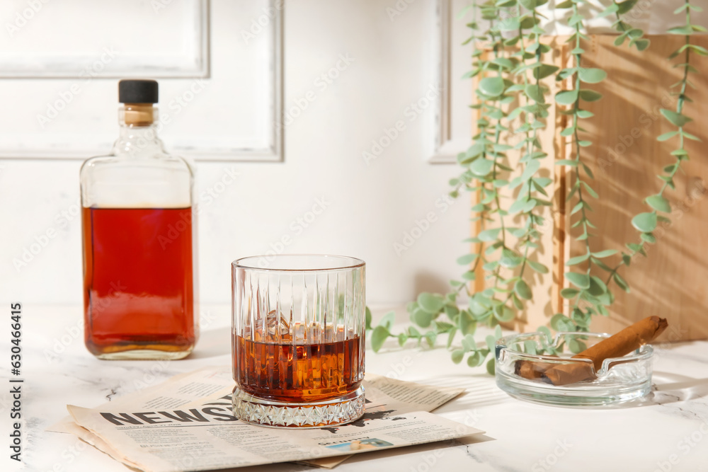 Glass of cold rum, newspaper and ash tray with cigar on table