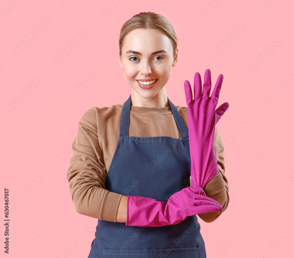 Young woman in rubber gloves on pink background