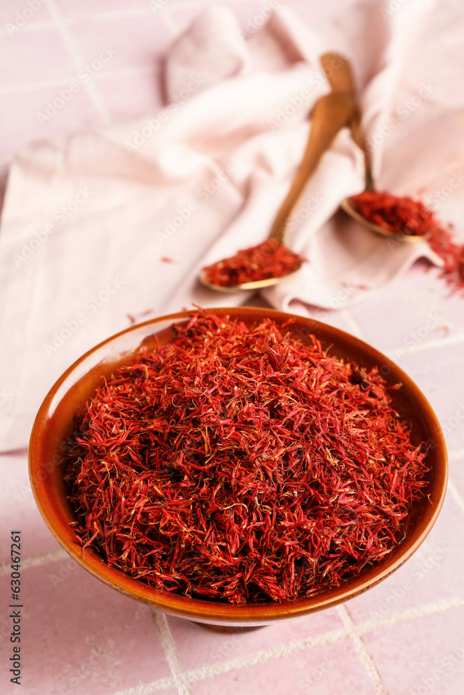 Bowl with pile of saffron on pink tile background