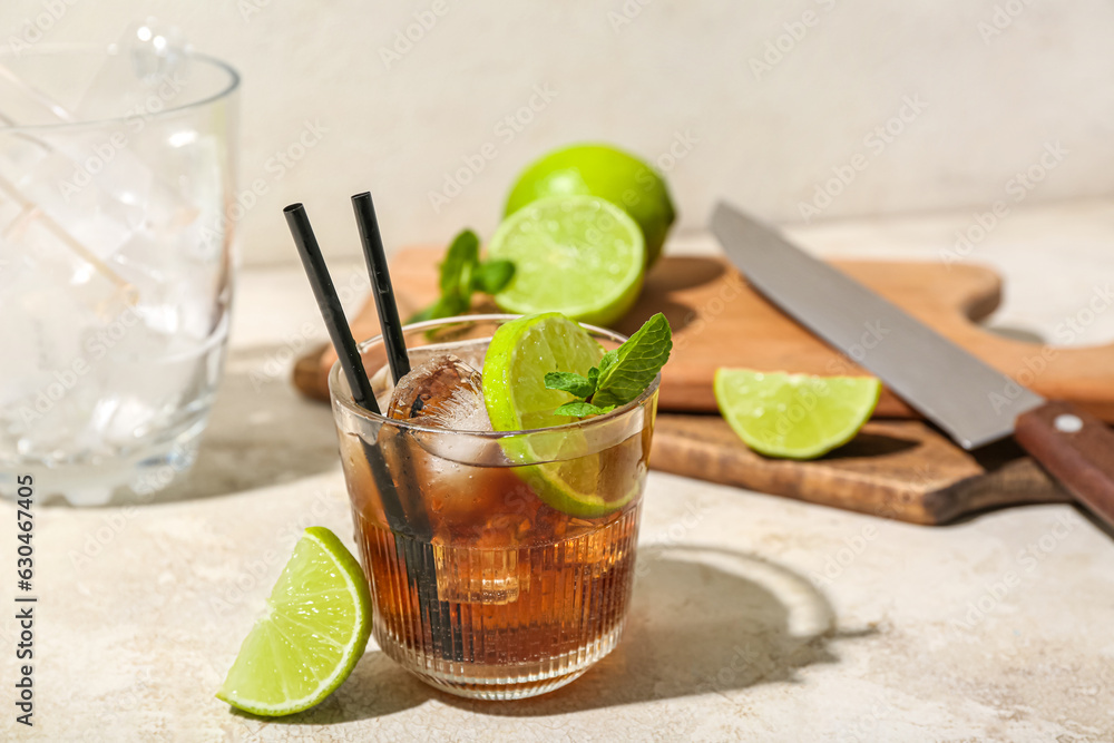 Glass of tasty Cuba Libre cocktail on light background