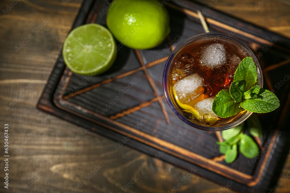 Glass of tasty Cuba Libre cocktail on dark wooden background