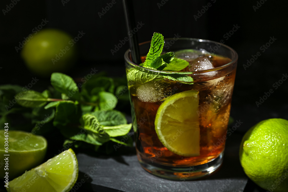 Glass of tasty Cuba Libre cocktail on dark background, closeup