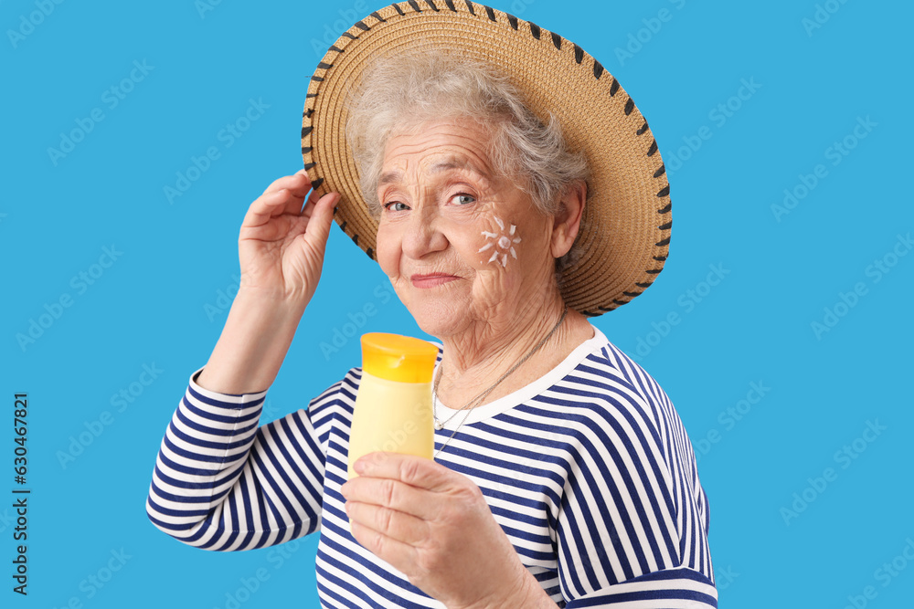 Senior woman with sunscreen cream on blue background