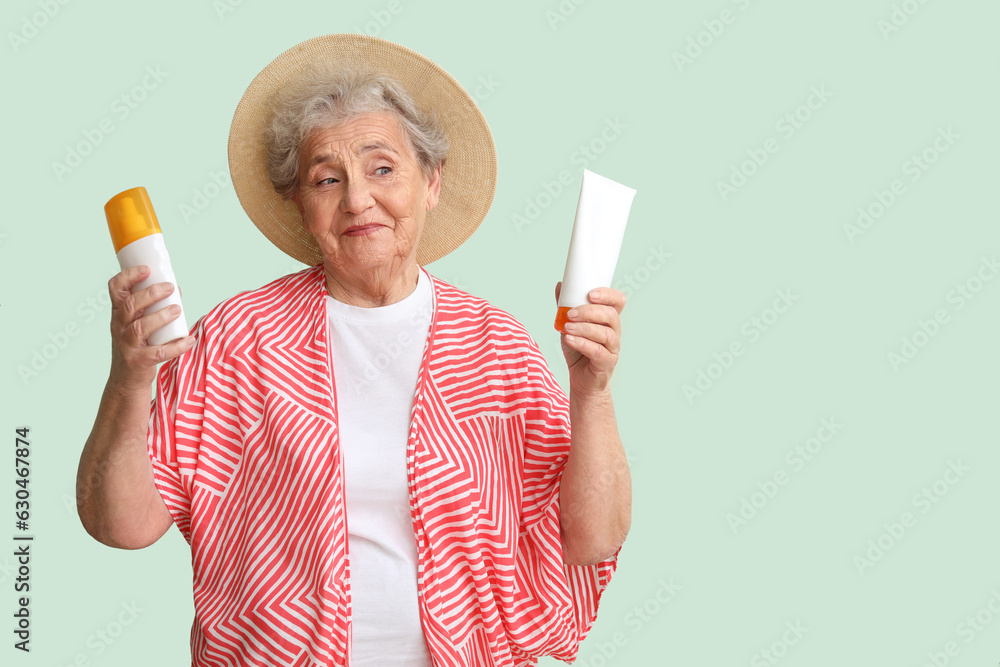 Senior woman with sunscreen cream on green background