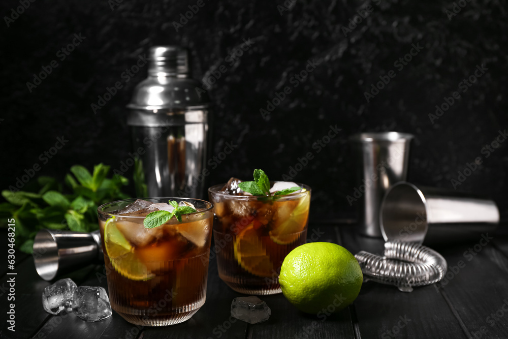 Glasses of cold Cuba Libre cocktail on dark background