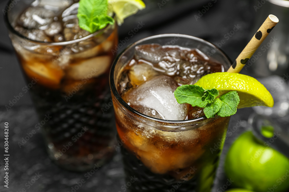 Glasses of cold Cuba Libre cocktail on dark background, closeup