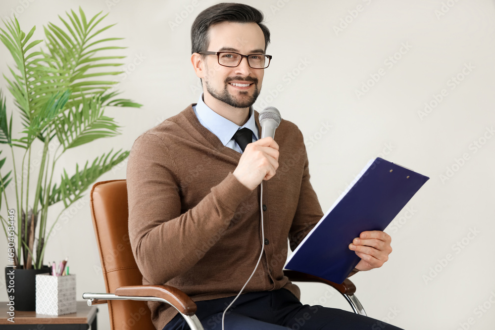 Male journalist with microphone having an interview in studio