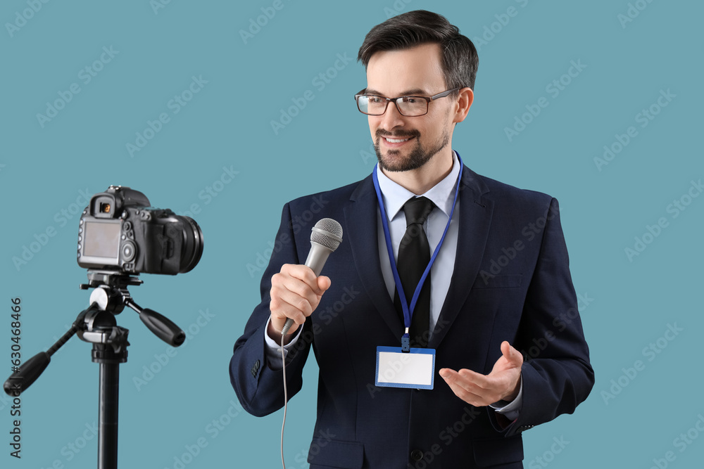 Male journalist with microphone recording video on blue background