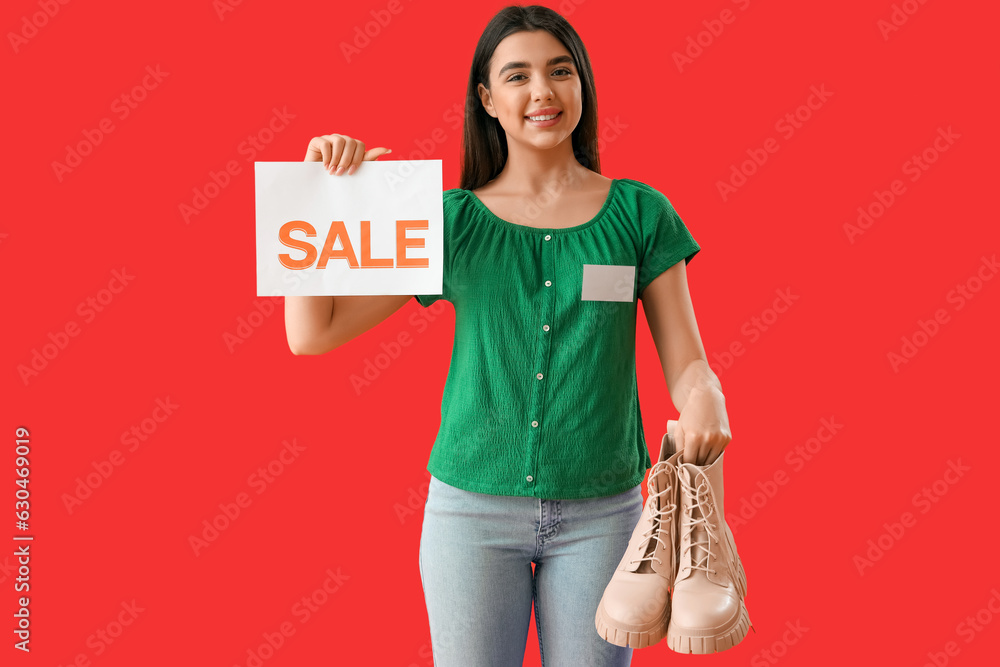 Female seller with sale sign and stylish boots on red background