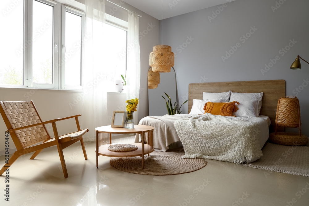 Interior of light bedroom with armchair, table and mirror