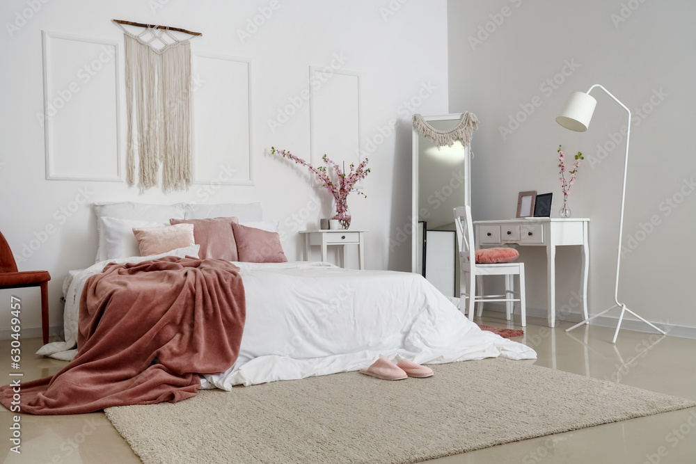 Interior of cozy bedroom with blooming tree branches in vase