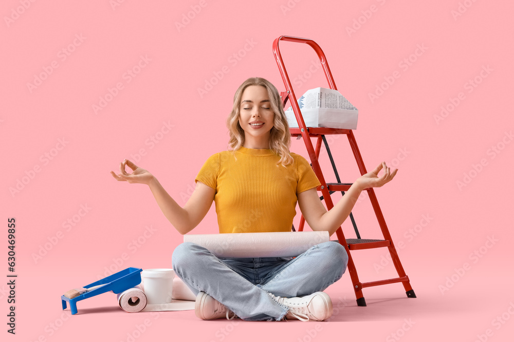 Young woman with wallpaper roll meditating on pink background