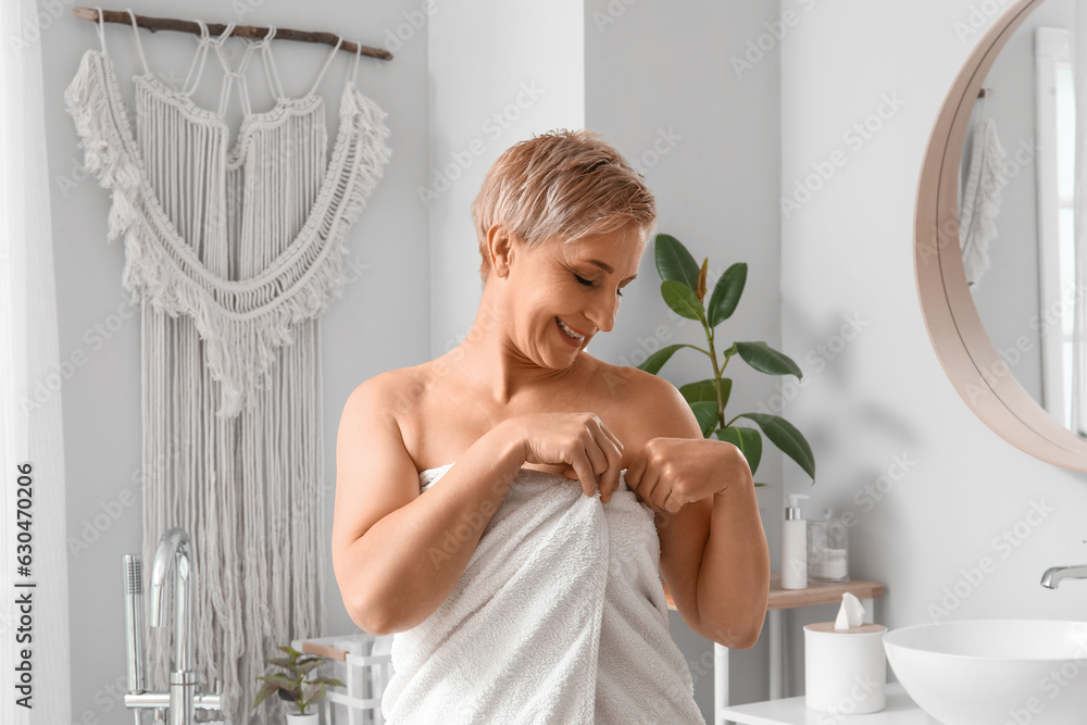 Mature woman with towel after shower in bathroom