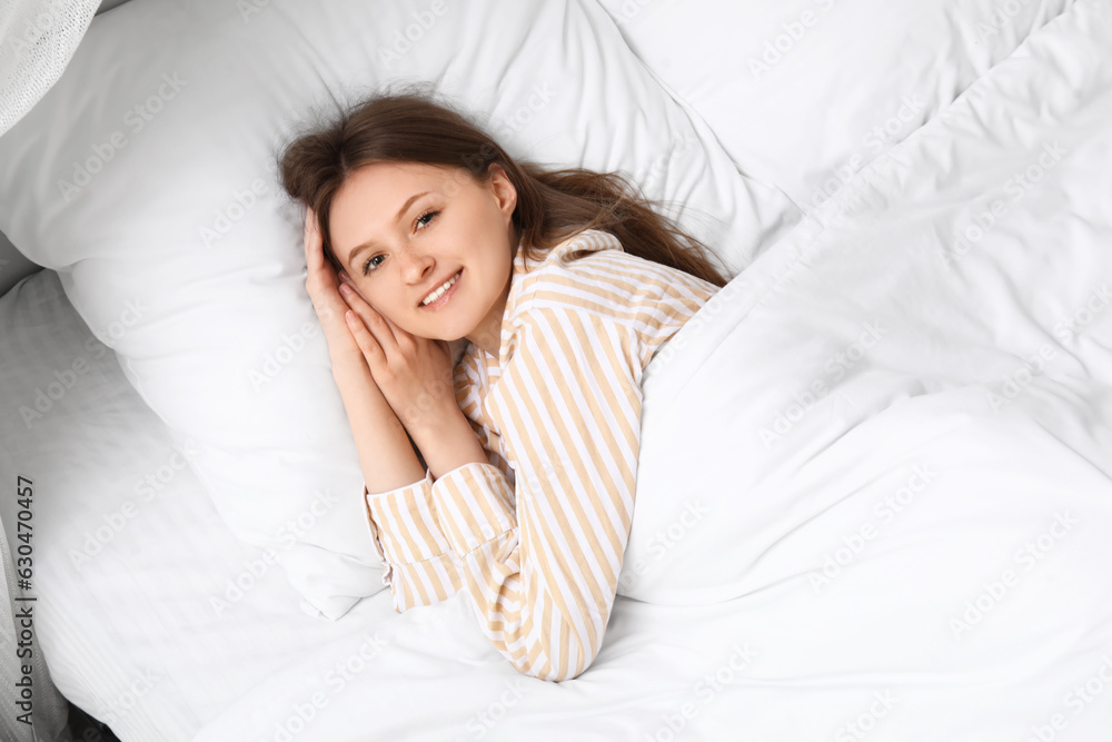 Morning of pretty young woman lying in soft bed, top view