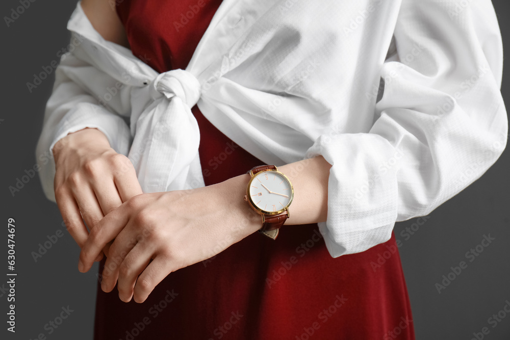 Elegant young woman with wristwatch on black background, closeup