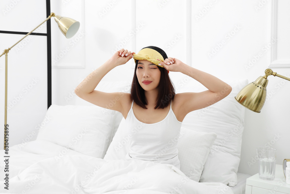 Beautiful Asian woman with sleeping mask in bedroom