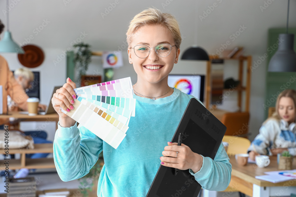 Female graphic designer with tablet and color palettes in office