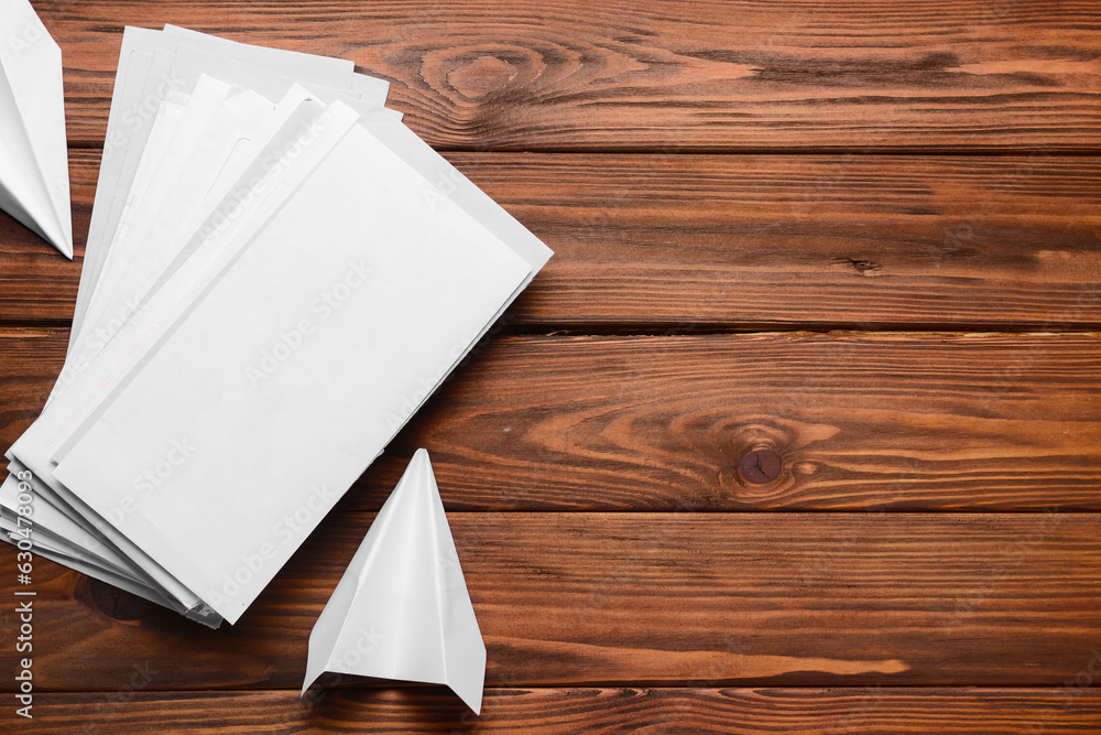 Stack of letters and paper planes on wooden background