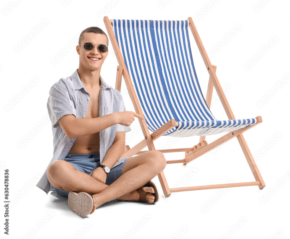 Teenage boy pointing at deck chair on white background