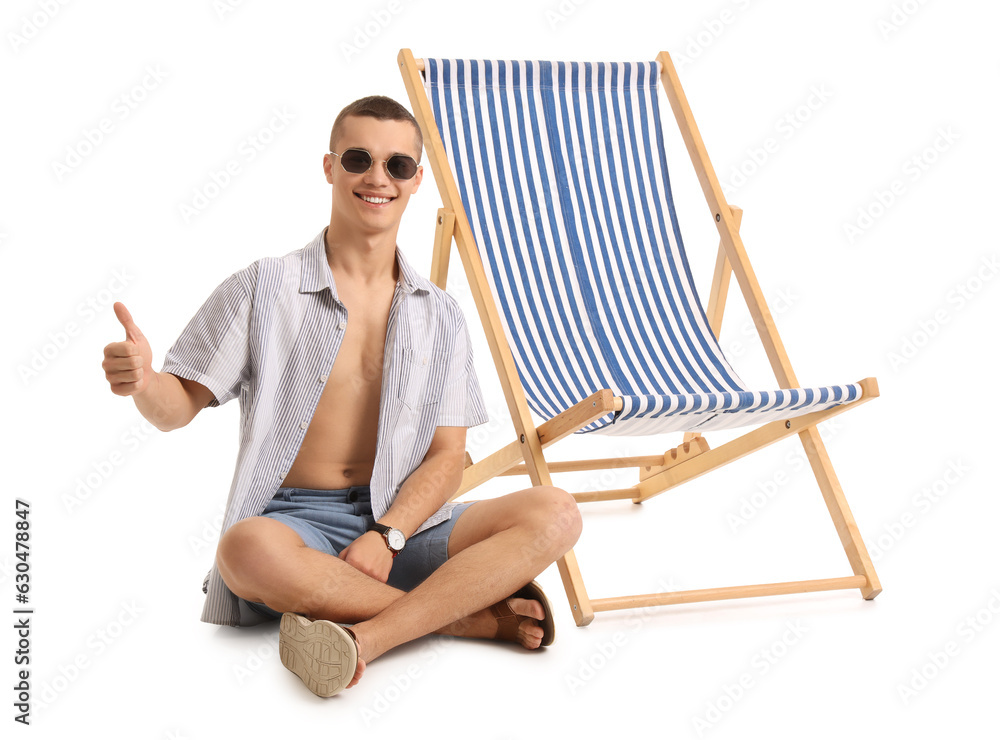 Teenage boy with deck chair showing thumb-up on white background