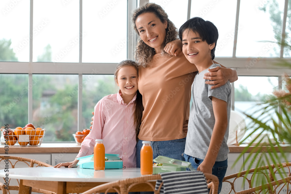 Mother hugging her little children before school in kitchen