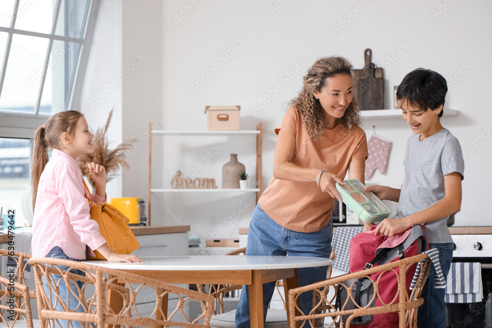 Mother with her little children packing school lunch in kitchen