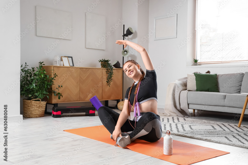 Sporty young woman training at home