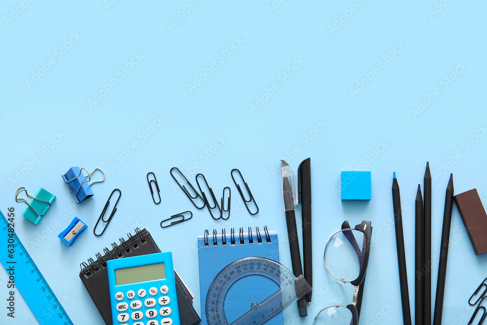 Different school stationery, notebooks and glasses on blue background