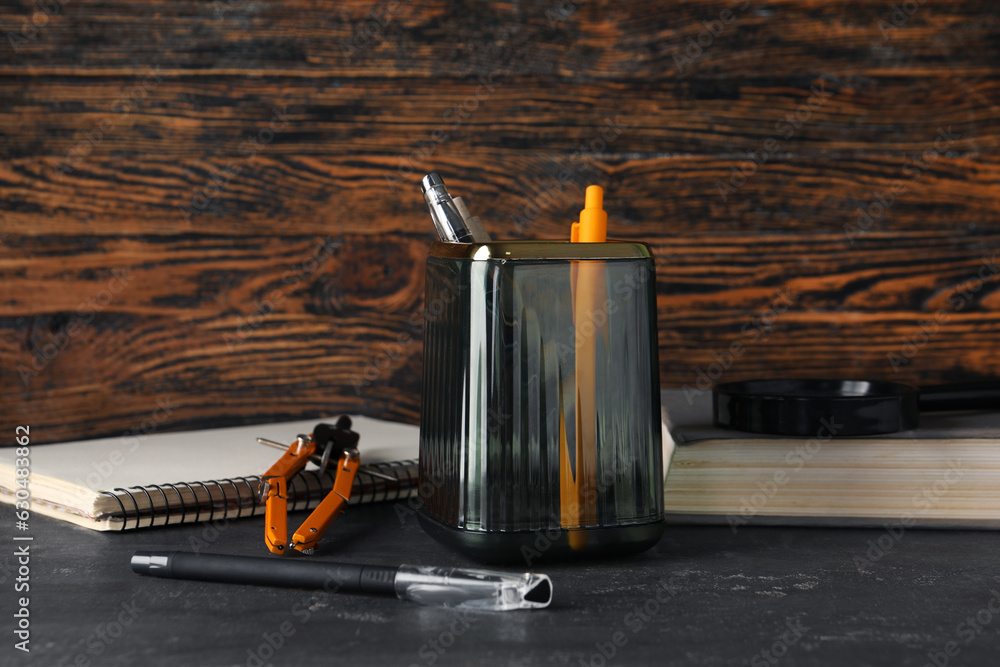 Glass holder with stationery on dark table