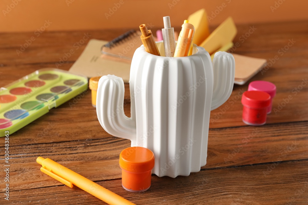 Stylish holder with different stationery on wooden table