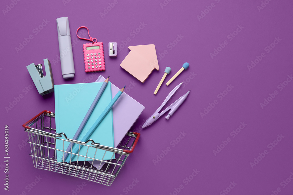 Composition with shopping basket and different stationery on purple background