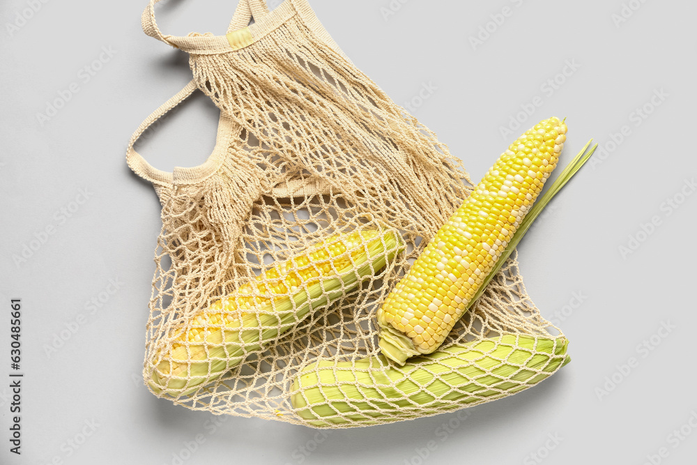 String bag with fresh corn cobs on white background