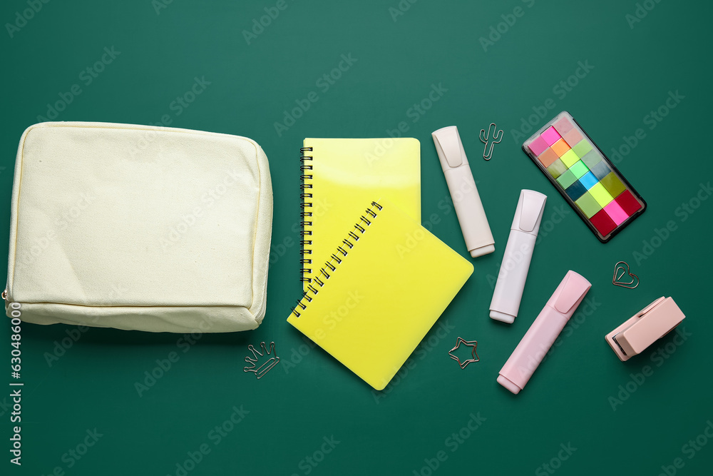 Pencil case with different school stationery on green background