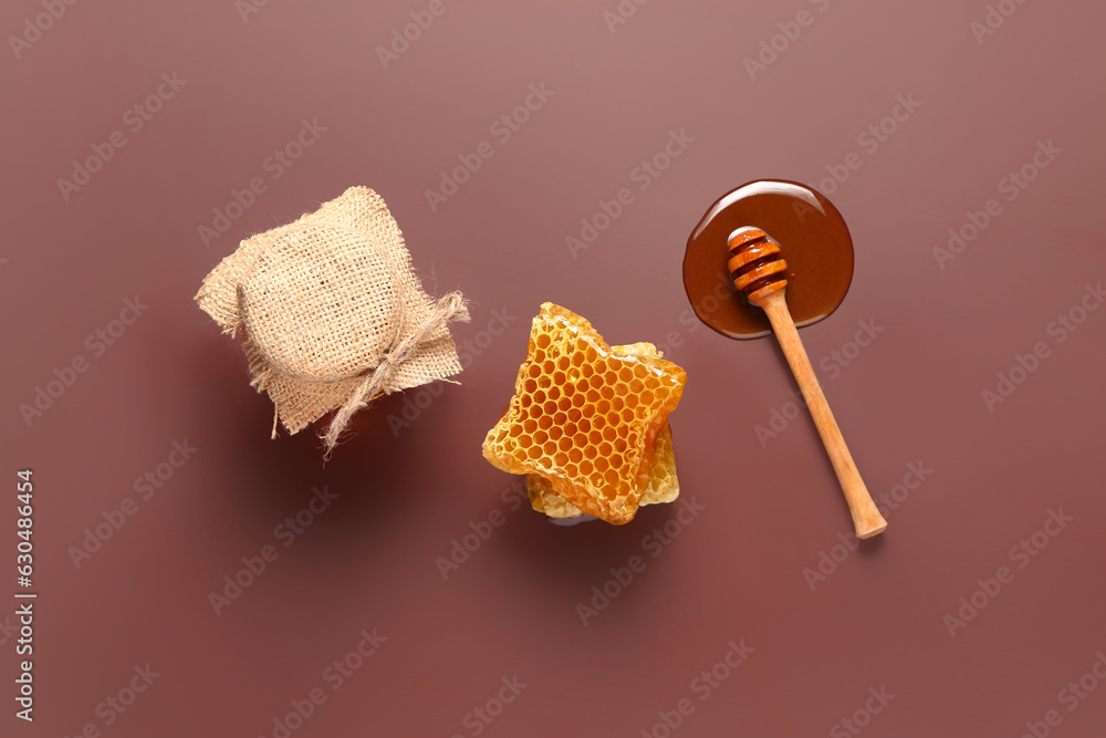 Jar of sweet honey with combs and dipper on red background