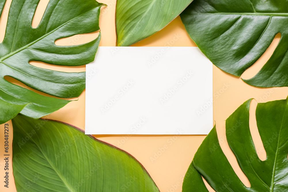 Blank card with different tropical leaves on orange background