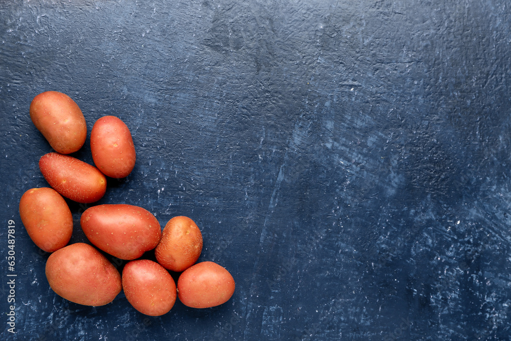 Fresh raw potatoes on blue background