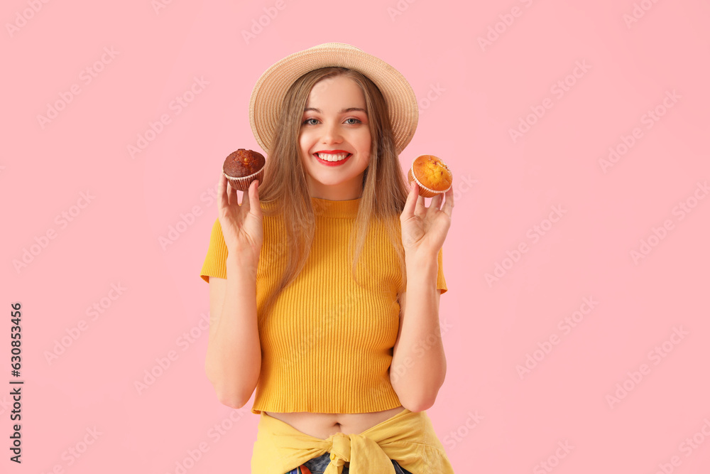 Young woman in hat with tasty muffins on pink background