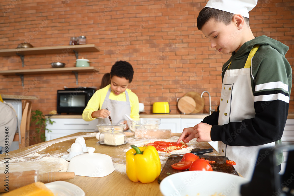 Little boy preparing pizza during cooking class in kitchen